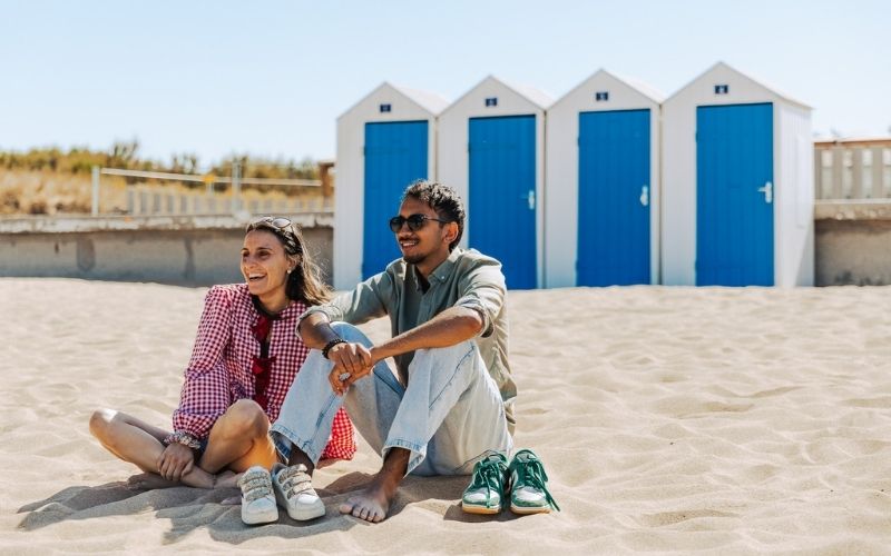 Couple assis sur une plage à Saint Jean de Monts en Vendée avec cabine de plage en fond