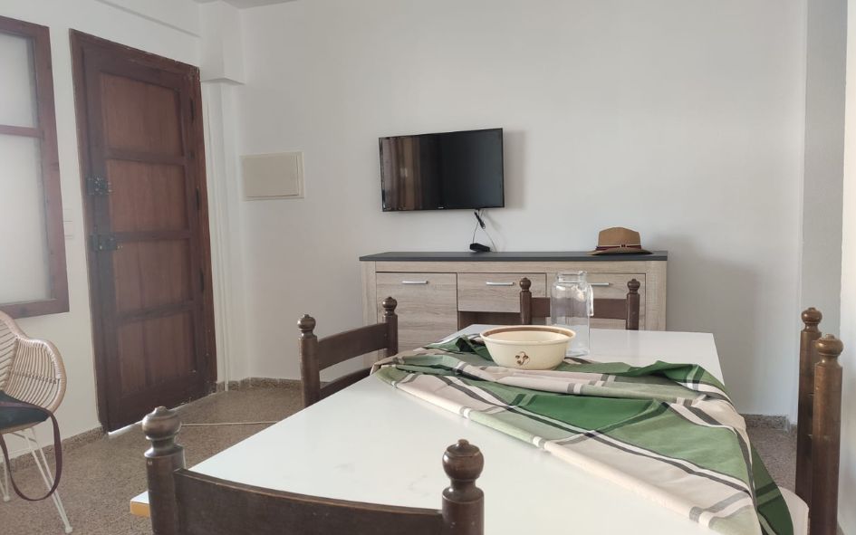 Salle à manger avec table et télévision dans les appartements Mestre sans clim à Oliva