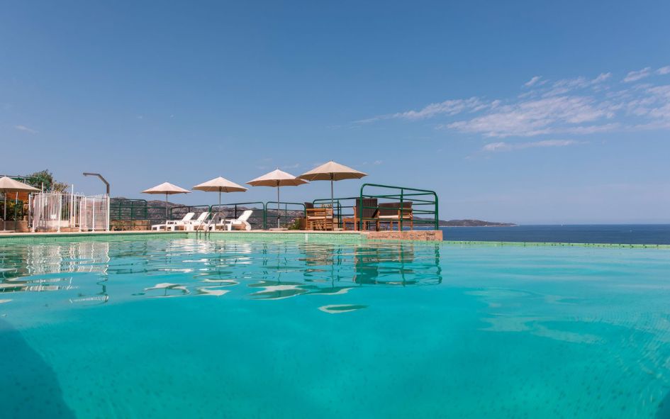 Piscine à débordement avec transats et parasols à la résidence Costa d'Oru en Corse