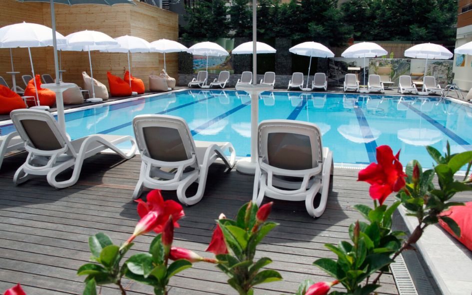 Piscine extérieure centrale avec transats et parasols au AMH Hôtel de Durres
