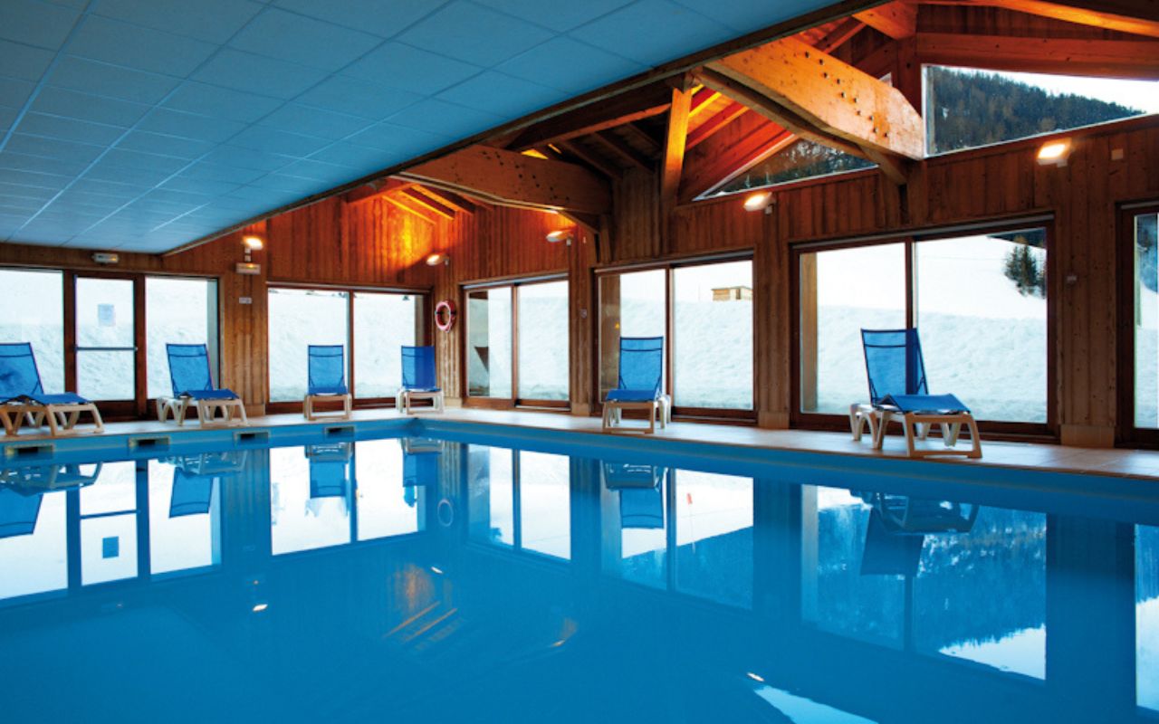 Belle piscine intérieure et chauffée avec vue sur les paysages enneigés depuis la résidence Les Valmonts