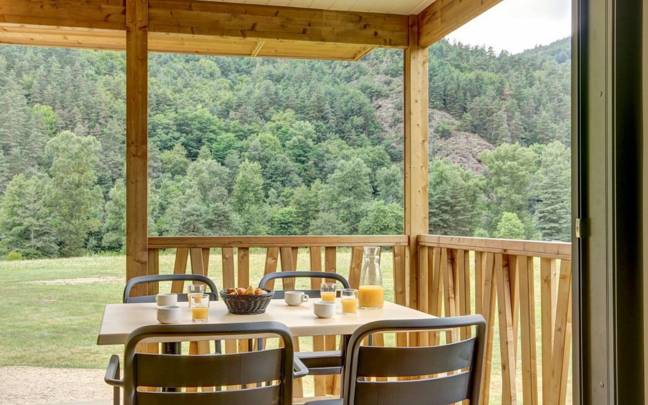 Terrasse aménagée d'un logement du village Club d'Alleyras avec vue dégagée sur la nature environnante pour des vacances au calme